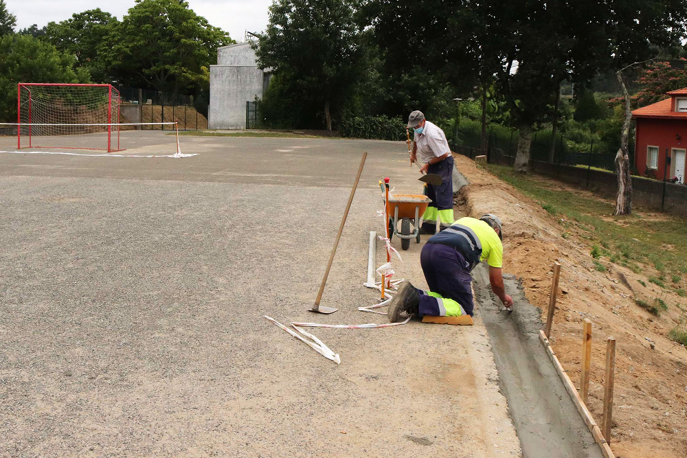 Operarios realizando traballos de mantemento na pista polideportiva do CEIP de Pedrouzos